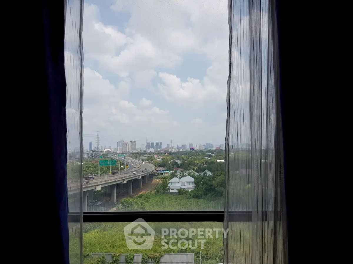 Stunning cityscape view from a high-rise window overlooking lush greenery and urban skyline.