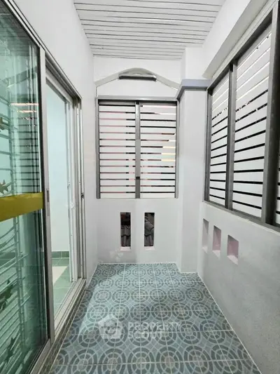 Charming enclosed balcony with modern sliding glass doors and stylish patterned floor tiles.