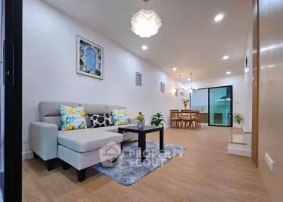 Modern living room with stylish decor and open layout leading to dining area and kitchen.