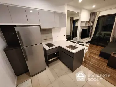 Modern open-layout kitchen with sleek cabinets and stainless steel appliances in a stylish apartment.