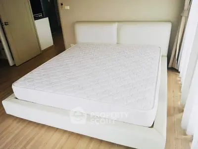 Spacious bedroom with modern white bed and natural light
