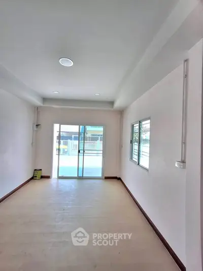 Spacious empty room with large windows and sliding glass door leading to balcony.