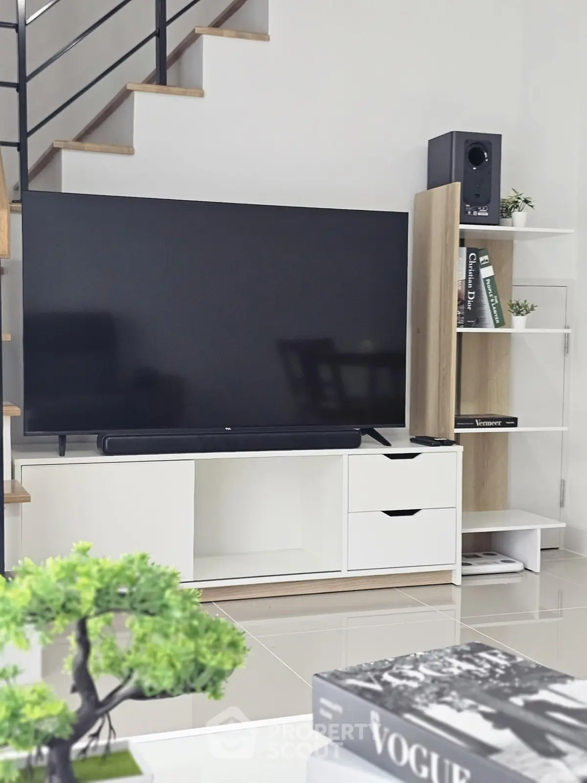 Modern living room with sleek TV setup and stylish shelving under staircase