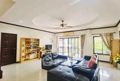 Spacious living room with modern black leather sofas and large windows offering natural light.