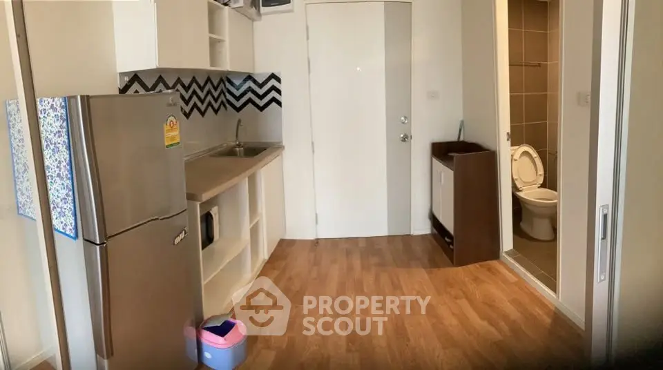 Compact kitchen with modern appliances and adjacent bathroom in cozy apartment.