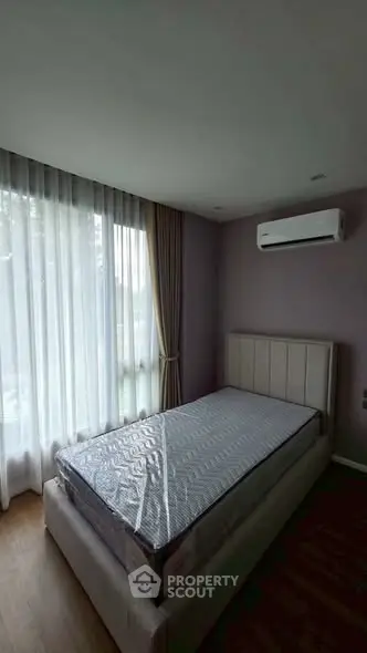 Cozy bedroom with natural light and air conditioning, perfect for relaxation.