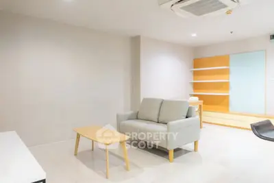 Modern minimalist living room with cozy sofa and sleek wooden furniture.