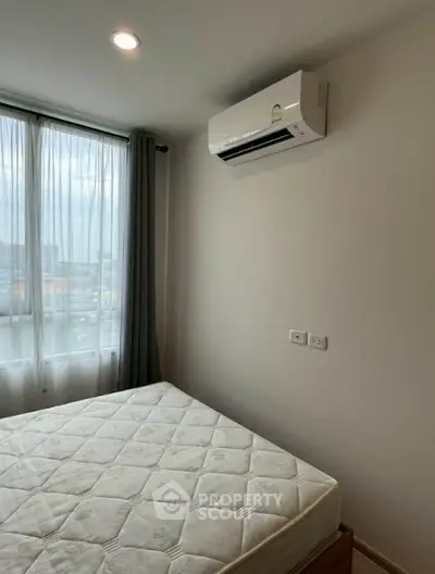 Cozy bedroom with large window and air conditioning, perfect for comfortable living.