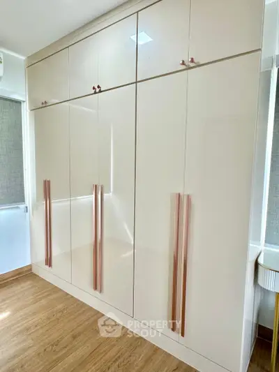 Spacious modern wardrobe with sleek design and ample storage in a bright room with wooden flooring.