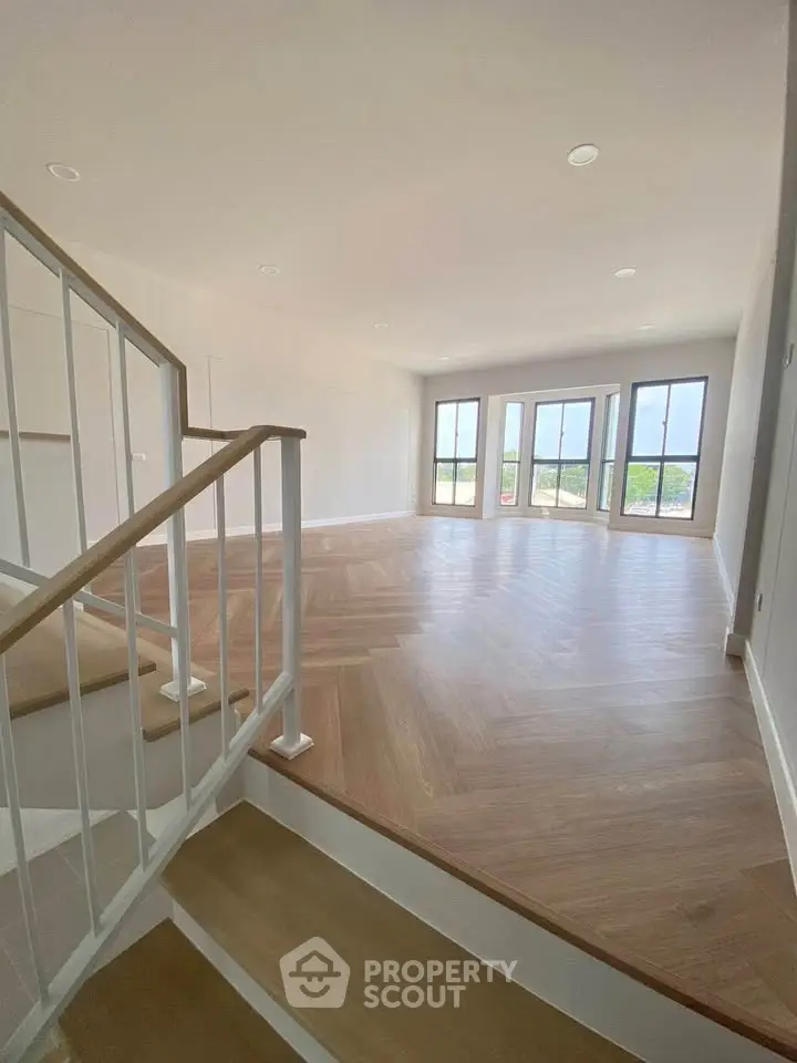 Spacious living room with elegant wooden flooring and large windows offering stunning views.