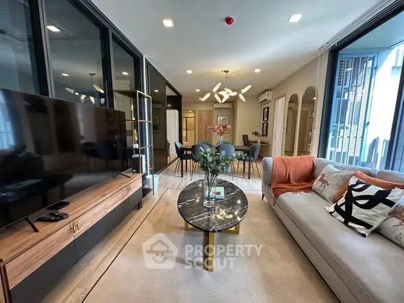 Modern living room with stylish decor and open layout, featuring a large TV and elegant furniture.