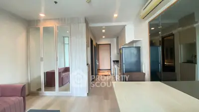 Modern apartment interior with sleek kitchen and cozy living area, featuring mirrored wardrobe and stylish decor.
