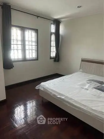 Spacious bedroom with large windows and elegant wooden flooring