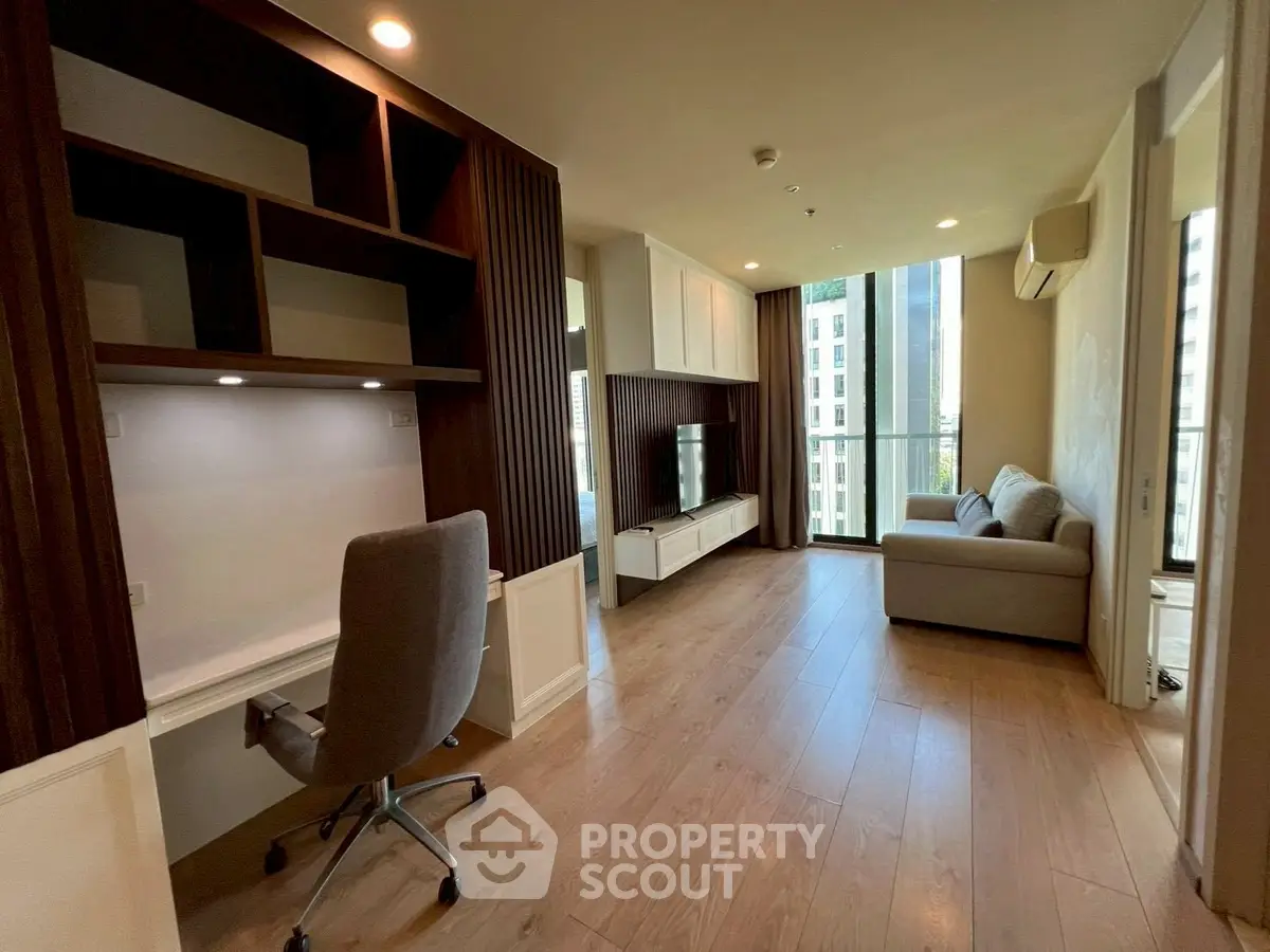 Modern living room with study area and large windows in a stylish apartment.