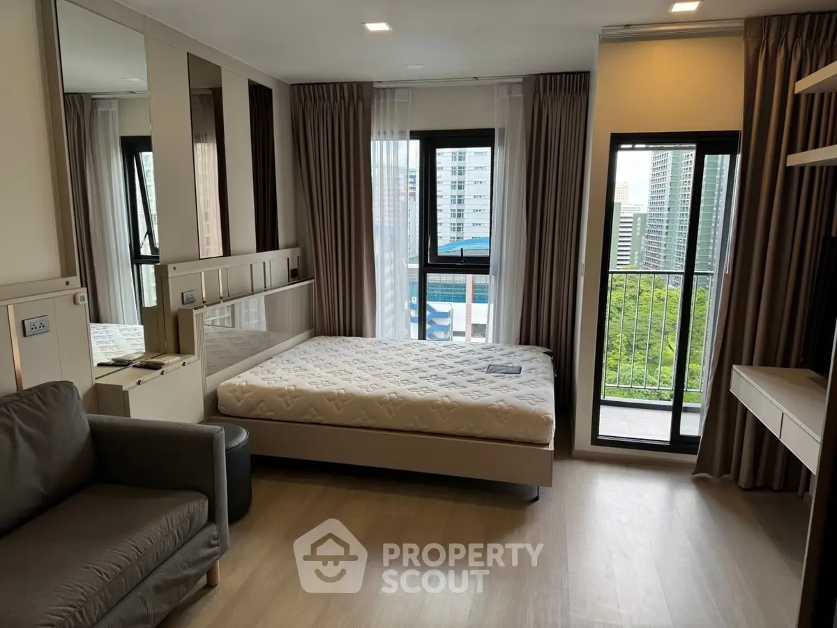 Modern bedroom with city view and balcony access in high-rise apartment