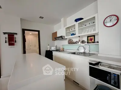 Modern kitchen with sleek white cabinets and island, featuring open shelving and contemporary decor.