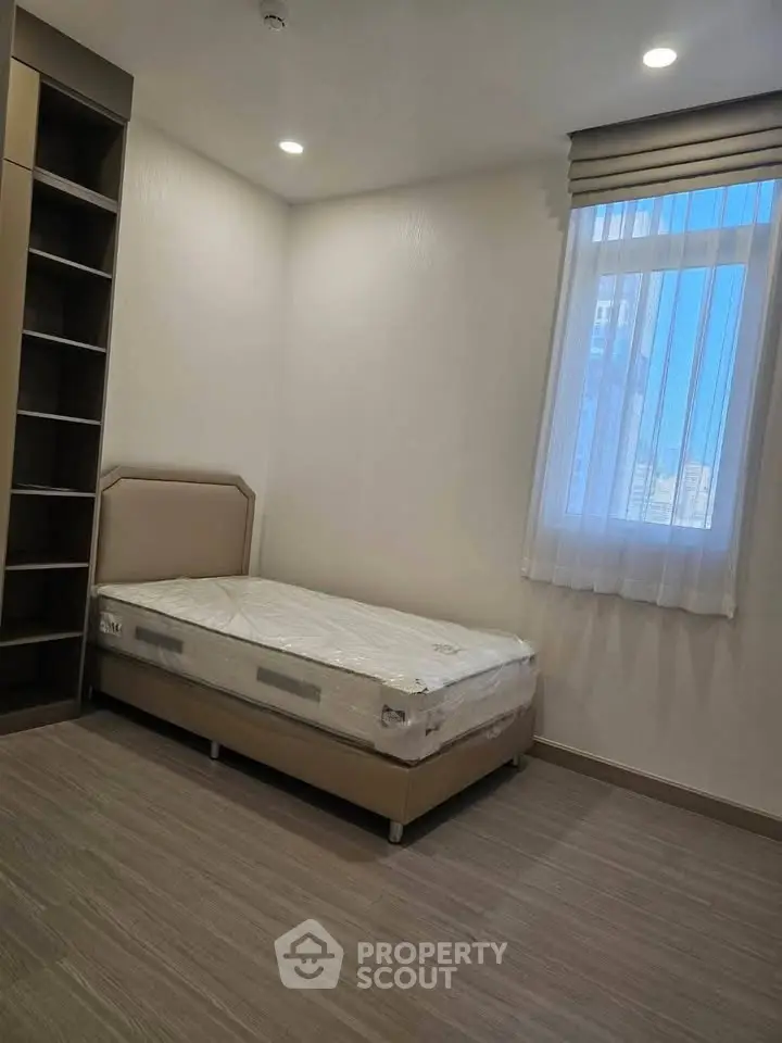 Cozy bedroom with single bed and built-in shelving, perfect for minimalist living.