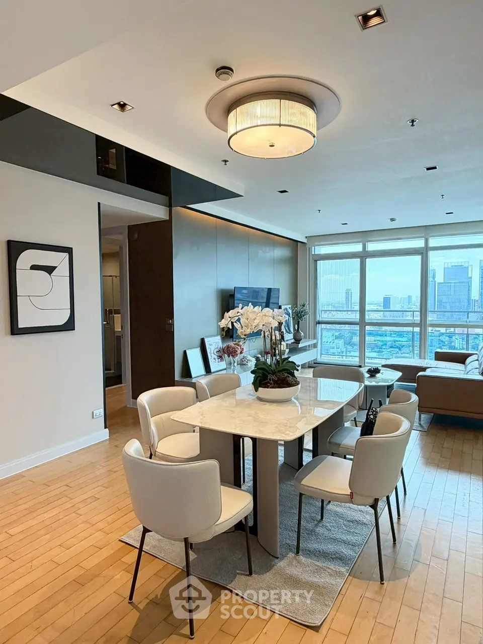 Modern living room with dining area and city view, featuring elegant decor and natural light.