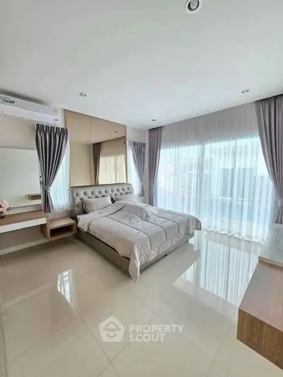 Spacious bedroom with elegant decor and large windows for natural light