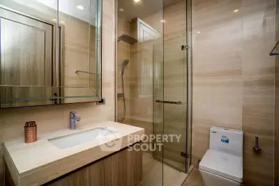 Modern bathroom with glass shower and sleek fixtures in luxury apartment.