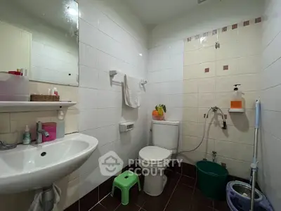 Cozy bathroom with modern fixtures and tiled walls, featuring a sink, toilet, and shower area.