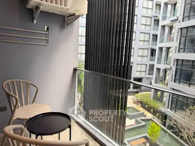 Modern balcony with seating overlooking contemporary apartment complex and garden view.