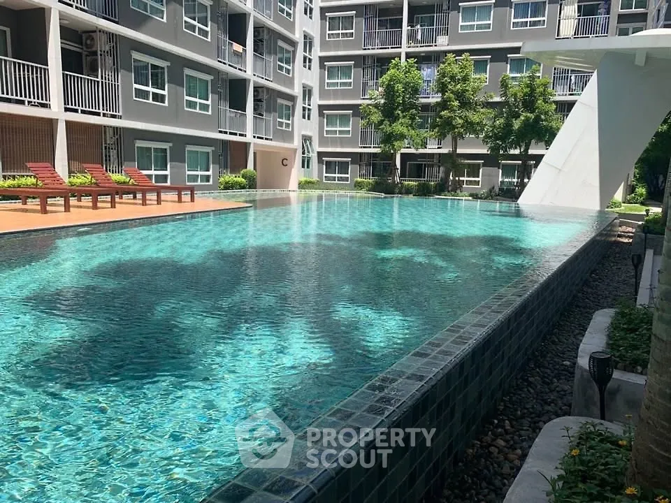 Luxurious apartment complex with stunning outdoor pool and sun loungers, perfect for relaxation.