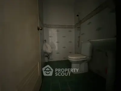 Cozy bathroom with green tiled floor and classic fixtures, perfect for a compact space.