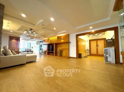 Spacious living room with modern lighting and wooden flooring, perfect for family gatherings.