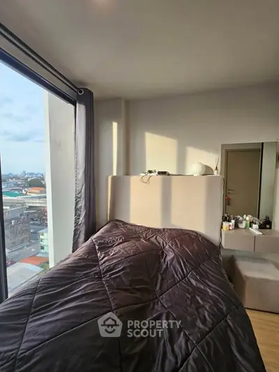 Cozy bedroom with city view, modern decor, and ample natural light.