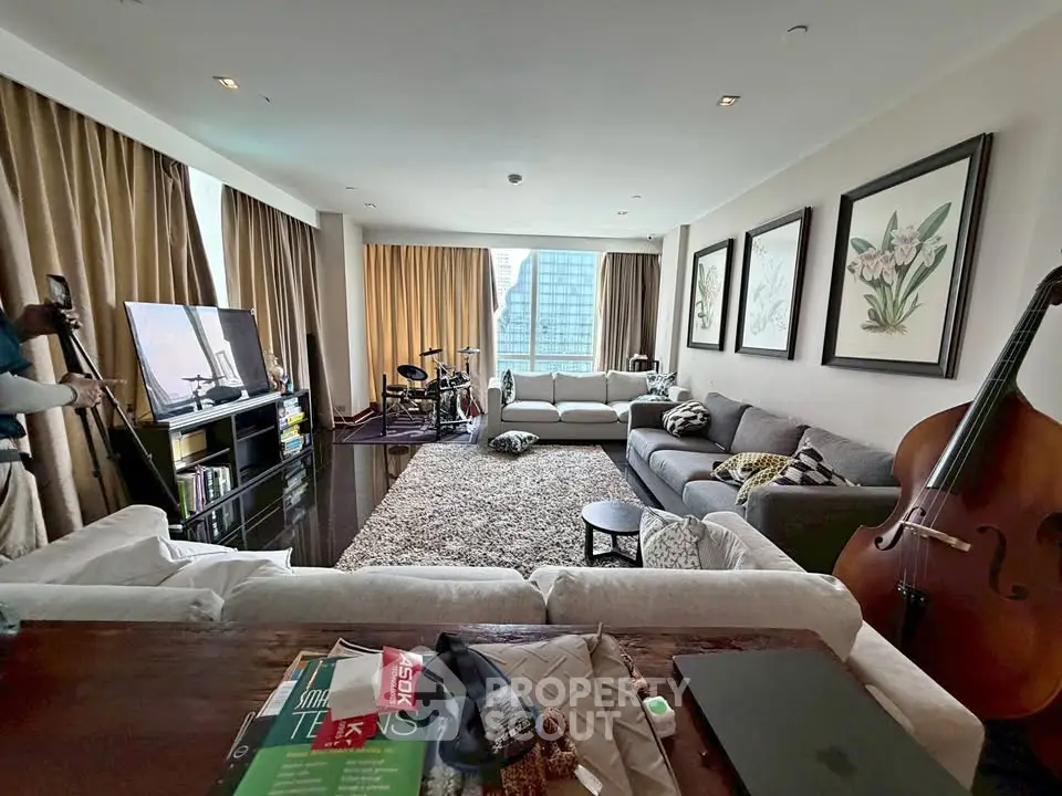 Spacious living room with modern decor and city view, featuring cozy seating and musical instruments.