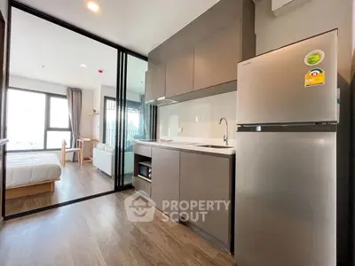 Modern studio apartment with sleek kitchen and cozy bedroom, featuring large windows and stylish decor.
