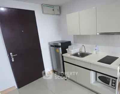 Modern compact kitchen with sleek cabinetry and built-in appliances in a stylish apartment.