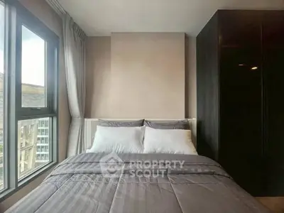 Cozy bedroom with large window offering city views and modern decor.