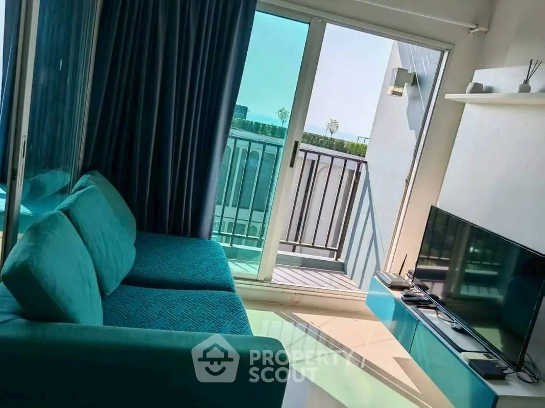 Modern living room with teal sofa and balcony view, perfect for relaxation.