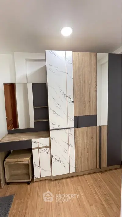 Modern bedroom with stylish wardrobe and vanity set, featuring wood and marble textures.