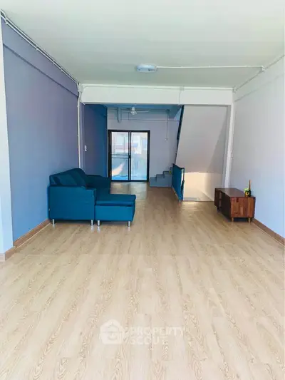 Spacious living room with modern blue sofa and wooden flooring, featuring a bright open layout.