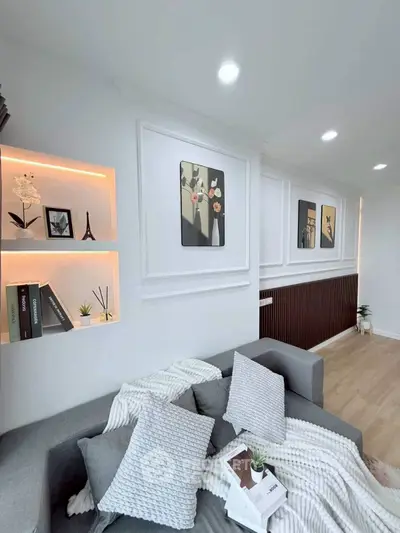Modern living room with stylish decor and cozy gray sofa, featuring elegant wall art and ambient lighting.