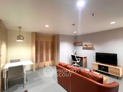 Modern living room with leather sofa, TV, and study desk in open layout apartment.