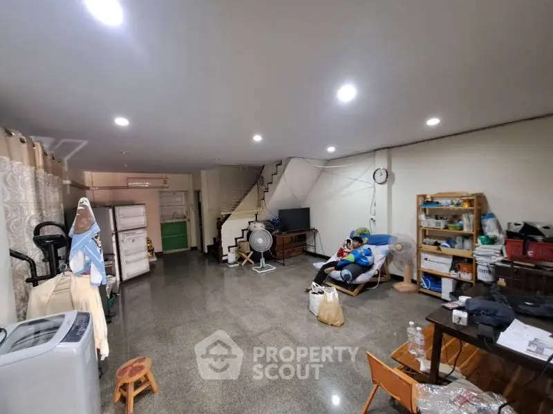 Spacious living area with modern lighting and open layout, featuring a cozy seating area and practical storage solutions.