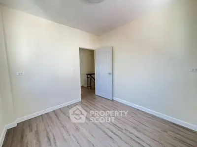 Spacious empty room with wooden flooring and white walls, perfect for customization.