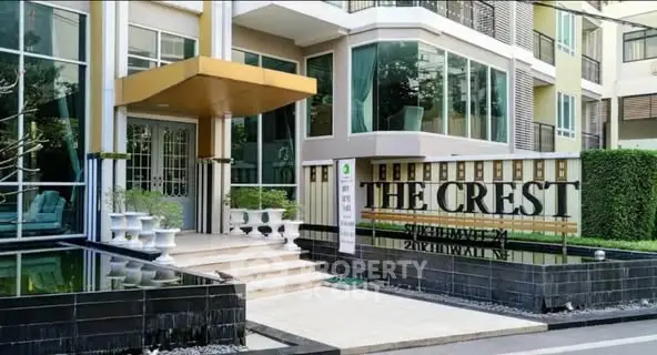 Modern apartment building entrance with stylish design and lush greenery.