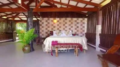 Charming rustic bedroom with wooden beams and cozy decor in tropical setting.