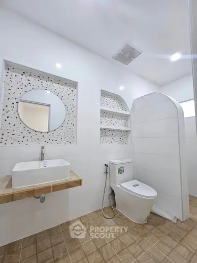 Modern bathroom with stylish sink and toilet, featuring elegant tile design and built-in shelves.