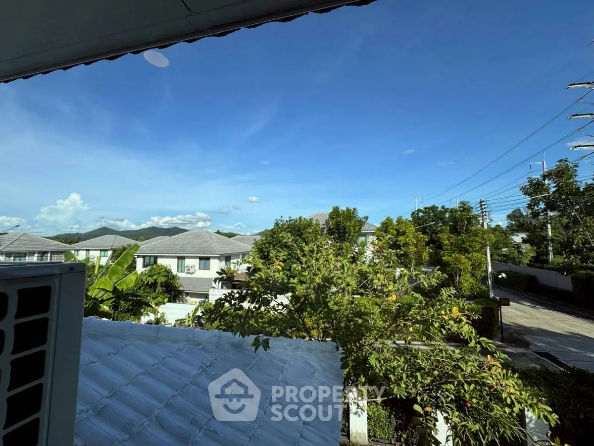 Scenic view from a residential property showcasing lush greenery and neighboring houses under a clear blue sky.