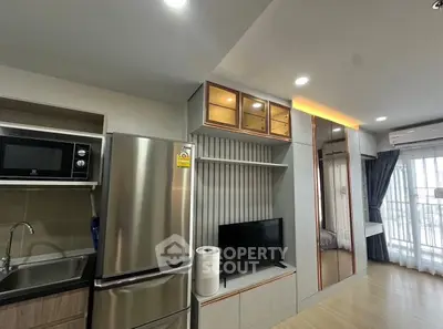 Modern apartment interior with sleek kitchen and cozy living area, featuring stainless steel appliances and stylish decor.
