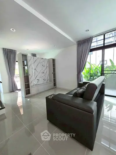 Spacious modern living room with sleek sofa and large windows for natural light.