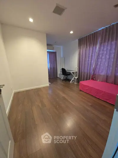 Spacious bedroom with wooden flooring and modern furnishings