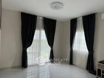 Spacious empty room with large windows and elegant dark curtains