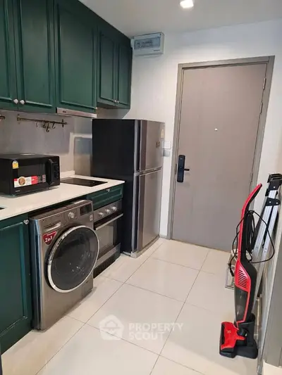Modern kitchen with green cabinets, stainless steel appliances, and sleek white flooring.